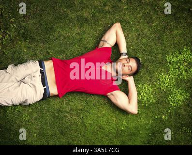 Gut aussehend, passen Männermodel entspannende liegend auf dem Rasen, Blick in die Kamera, direkt von oben fotografiert Stockfoto
