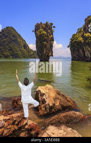 Frau führt Yoga Pose Tree am Ufer der Andamanensee aus. Exotischer Urlaub in Thailand Stockfoto