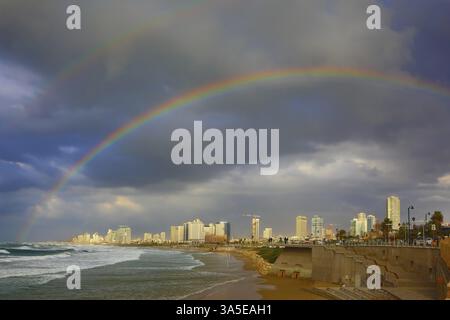 Promenade und Strand in Tel Aviv. Sturmwolke, die über dem Meer hing, herrlicher riesiger Regenbogen überquerte den Himmel Stockfoto