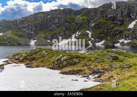 Kalter Sommer in Norwegen. Fahren Sie auf der Straße 520. Große Schneefelder blieben im Tiefland und an den Hängen der Berge. Eissee umgeben von gre Stockfoto