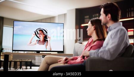 Mann und Frau entspannen sich auf dem Sofa und schauen im dunklen Wohnzimmer fern Stockfoto