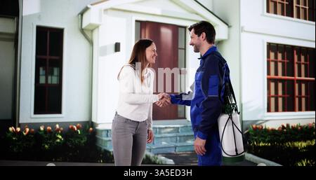 Glückliche Frau und junge Schädlingsbekämpferin, die vor dem Haus die Hände schütteln. Stockfoto