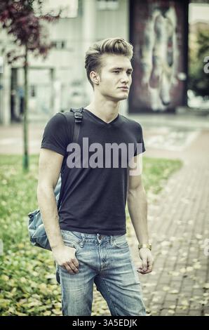 Attraktiven jungen Mann in der Stadt Umgebung, mit Rucksack auf der Schulter Stockfoto