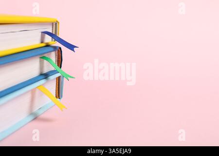 Bücher mit Lesezeichen auf rosafarbenem Hintergrund, Großaufnahme. Leerzeichen für Text Stockfoto