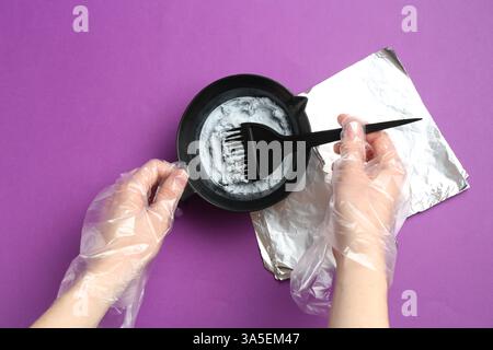 Frau, die Haarbleichmischung auf violettem Hintergrund herstellt, Draufsicht Stockfoto