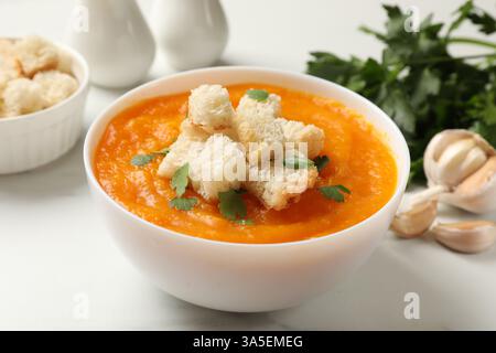 Köstliche Kürbiscremesuppe mit Croutons, Petersilie und Zutaten auf Lichttisch, Nahaufnahme Stockfoto