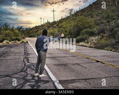 Der Rücken eines jungen Mannes, ein Anhalter, der in der Stadt auf ein Auto wartet, in Arizona, USA, Nordamerika mit Kapuzenpullover Stockfoto
