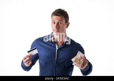 Junger Mann hält Banknoten und Kreditkarten, die Wahl zwischen den zwei Zahlungsmittel. Isoliert, Studio gedreht Stockfoto