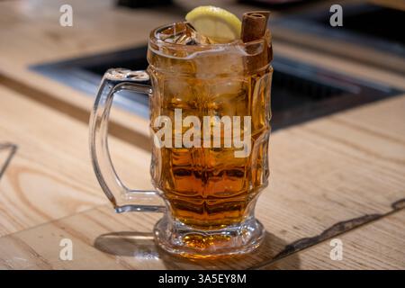 Ein Glas Whiskey mit Zitrone und Zimt auf dem Tisch Stockfoto