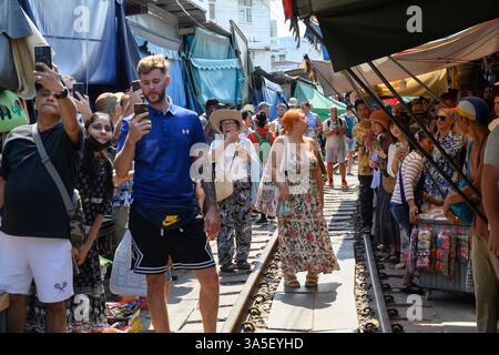Mae Klong, Thailand. März 2025. Touristen machen Fotos auf den Bahnlinien, wenn der Zug 14,30 am Bahnhof Maeklong, Samut S, ankommt Stockfoto