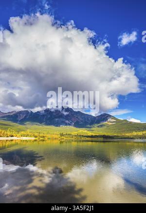 Frostiger Morgen in den Rocky Mountains, Kanada. Pyramid Mountain und herrliche Cumulus Wolken spiegeln sich im glatten Wasser des Lake Pyramid Stockfoto