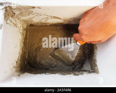 Cement powder Mixed by hand and Metal trowel. Wall Painting Preparation at home Stockfoto