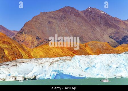 Patagonien. See und Gletscher Viedma. Vom Gletscher abgebrochene Eisstücke treiben im See. Ein kleines Touristenschiff nähert sich einem riesigen blau-weißen gl Stockfoto