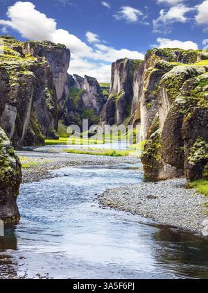 Steile Klippen, mit grünem Moos bewachsen, umgeben von einem sehr schnellen Fluss mit kaltem Wasser. Canyon Isländische Märchen und Legenden - Fyadrarglyufur Stockfoto