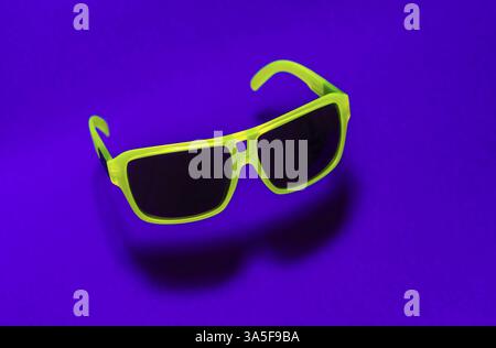 Helle grüne Farbe Sonnenbrille in der Luft. Grüne, die in der Luft schweben Sonnenbrille auf lila Hintergrund. Untere Schatten unterhalb der Gläser. Minimalismus summ Stockfoto