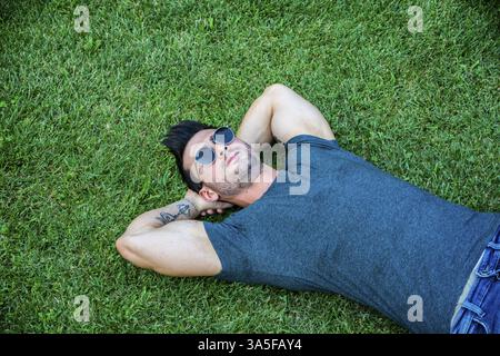 Gut aussehend, passen Männermodel entspannende liegend auf dem Rasen, Blick in die Kamera, direkt von oben fotografiert Stockfoto