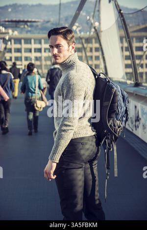 Hübscher junger Mann zu Fuß in die Stadt mit Rucksack auf der Schulter, tragen Winterkleidung Stockfoto