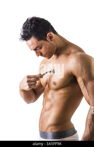 Nahaufnahme gutaussehender muskulöser junger Mann, der seine Brust mit dem manuellen Rasierer rasiert, isoliert auf weißem Hintergrund Stockfoto