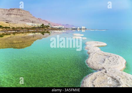 Israel. Am frühen Morgen in den Resorts des Toten Meeres. Das azurblaue Meerwasser ist voller heilender Salze. Kleine Inseln und Salzpfad im Wasser. Konzept von Stockfoto