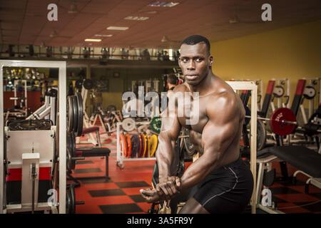 Attraktive Hunky schwarzen männlichen Bodybuilder Bodybuilding Pose im Fitness-Studio zu tun Stockfoto