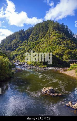 Reisen Sie nach Neuseeland, Nordinsel. Karangahake-Schlucht. Der Fluss fließt zwischen verlassenen Goldminen. Der blaue Himmel spiegelt sich im Wasser. Der Tiefenbereich Stockfoto