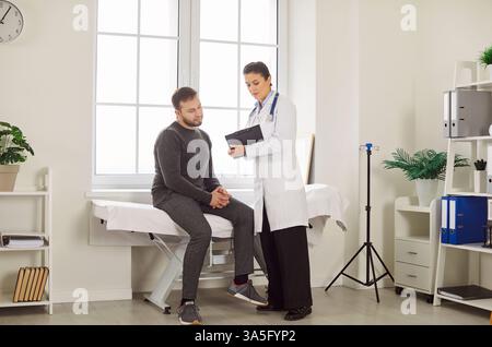 Liebevolle Ärztin in weißer medizinischer Uniform sprechen, Ergebnisse oder Symptome mit männlichem Patienten besprechen Stockfoto