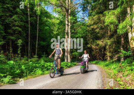 Leute, die Elektroroller auf Asphaltstraßen im Wald fahren. Gaderska-Tal im Großen Fatra-Gebirge in der Slowakei Stockfoto
