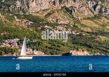 Segelboot schwimmt auf der Adria in Montenegro. Die Insel Saint Setafan im Hintergrund. Stockfoto