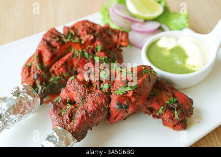 Ein Teil köstlicher Tandoori-Hühner, serviert mit Joghurt und Hari Chutney Stockfoto