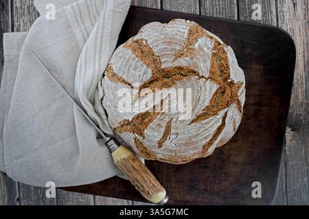 Hausgemachter Brotlaib auf einem Tuch und rustikalem Hirschhornmesser Stockfoto