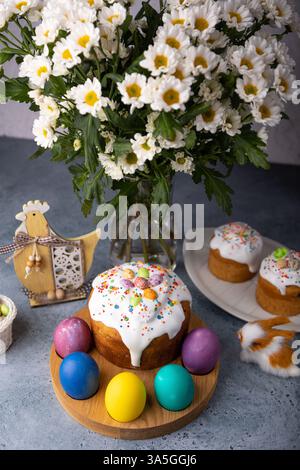 Osterkulich mit kandierten Früchten in weißer Glasur mit bunten Streuseln und bemalten Eiern. Traditionelles Ostergebäck. Osterferien. Nahaufnahme, wählen Sie Stockfoto