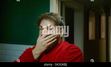 Junger Mann, der morgens gähnt und versucht aufzuwachen und sich schläfrig zu fühlen, mit Müdigkeit und Morgenroutine zu kämpfen Stockfoto