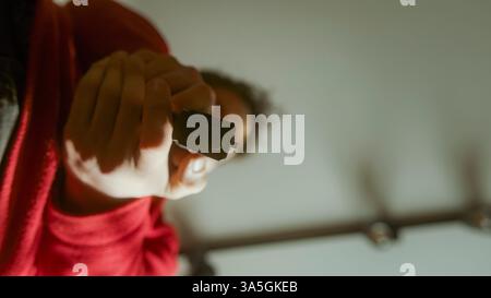Dramatische Nahaufnahme einer Person, die eine schwarze Pistole direkt auf die Kamera zeigt und in einer schwach beleuchteten, intensiven Szene feuert Stockfoto