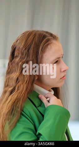 Die junge Frau fängt die Essenz der Besinnung ein und hält sanft ihren Blazer, ihr Profil offenbart ein ausgeglichenes und reflektierendes Verhalten. Stockfoto