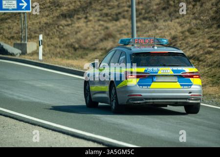 A9, Deutschland - 23. März 2025: Ein Polizeiwagen fährt von der Autobahn in eine Raststätte. Das beleuchtete Schild zeigt POLIZEI auf Englisch und ist aktiviert. *** Ein Streifenwagen der Polizei fährt von der Autobahn auf einem Rastplatz. Die Leuchtschrift zeigt in englischer Sprache POLICE und ist aktiviert. Stockfoto