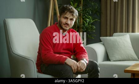 Mann, der in einem gemütlichen Wohnzimmer sitzt und warm und freundlich aussieht Stockfoto