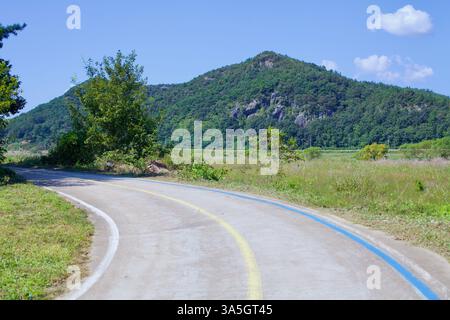 Naju City, Südkorea - 24. September 2020: Ein glatter Radweg schlängelt sich durch die ländliche Landschaft entlang des Yeongsangang Bike Path, mit einem bewaldeten Radweg Stockfoto