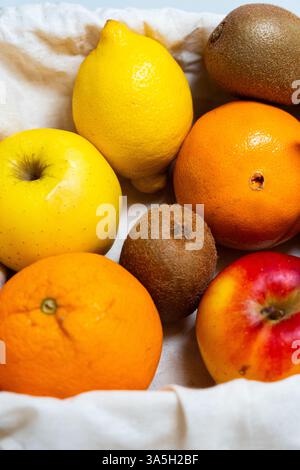 Eine bunte Mischung aus Früchten, einschließlich Äpfeln, sauren Zitronen, saftigen Kiwis und süßen Orangen, in einem sauberen Korb Stockfoto