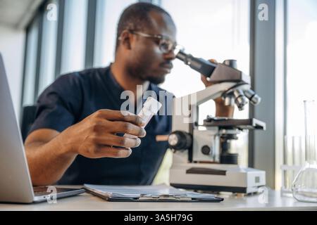 Recherchieren. Wissenschaftler arbeiten drinnen, das Mikroskop ist auf dem Tisch. Stockfoto
