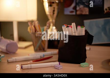 Die Anordnung von Markierungen in einem schwarzen Behälter auf dem Schreibtisch mit Trophäen und anderen Objekten im Hintergrund schafft einen künstlerischen Arbeitsbereich, der der Kreativität förderlich ist Stockfoto