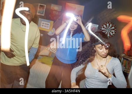 Gruppe von Freunden, die eine lebhafte Party in einem lebhaften Raum mit energiegeladenem Tanz und hellem Ambiente genießen, umgeben von fröhlicher Dekoration und fesselnden Aktivitäten Stockfoto