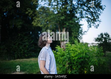 Junge Schüler, die die friedliche Atmosphäre der Natur genießen, während sie sich in einem Park entspannen Stockfoto