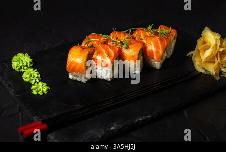 Lachsbrötchen auf schwarzem Schieferteller, in der Nähe von Wasabi und Ingwer Stockfoto