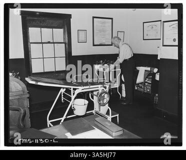 Dr. Anderson, ein Betriebsarzt, steht in der Ecke des Hauptbehandlungsraums an der Apotheke. Er betreut die medizinische Versorgung von Bergleuten in Big Sandy und Murraytown, wo viele Arbeiter der Kingston Pocahontas Coal Company leben. Das Foto wurde in Exeter Mine, Welch, McDowell County, West Virginia, aufgenommen. Stockfoto