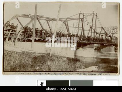 Ein Foto der Broadway Bridge über den Minnesota River in St. Peter, aufgenommen im April 1897 während eines Hochwassers. Das Bild zeigt Personen, die auf der Brücke stehen und in der Entfernung Kornelevatoren sichtbar sind. Stockfoto