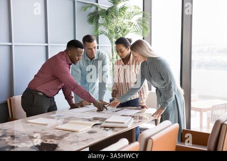 Multinationale Teamkollegen prüfen Daten mit Diagrammen und Diagrammen, nehmen an Brainstorming Teil, generieren Ideen und tauschen Lösungen aus Stockfoto