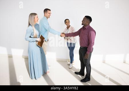 Verschiedene Geschäftsleute, Stakeholder, die sich bei der Besprechung im Flur des Firmenbüros mit der Kommunikation beschäftigen, lächeln, schütteln die Hände und bedanken sich gegenseitig Stockfoto