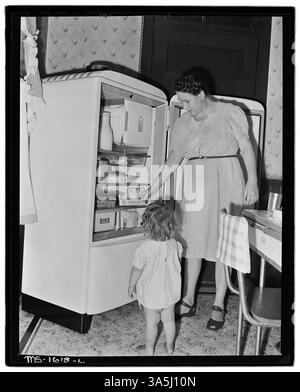 Mrs. E. R. Kunz und ihre Tochter stehen bei einem elektrischen Kühlschrank in ihrem Haus in Gary, McDowell County, West Virginia. Dem Haus fehlt fließendes Wasser, was die grundlegenden Lebensbedingungen der Bergbaufamilien widerspiegelt. Stockfoto