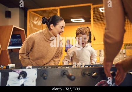 Spaß haben. Familie von Vater, Mutter und Sohn, die Tischfußballspiel drinnen spielen. Stockfoto