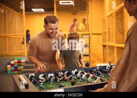Spaß haben. Familie von Vater, Mutter und Sohn, die Tischfußballspiel drinnen spielen. Stockfoto
